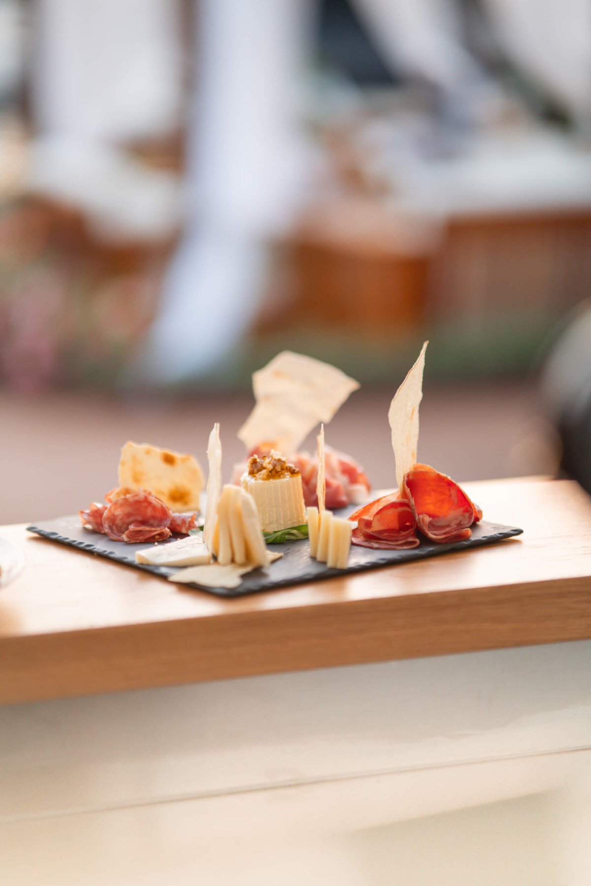 Charcuterie board on a black slate resting on a wooden board