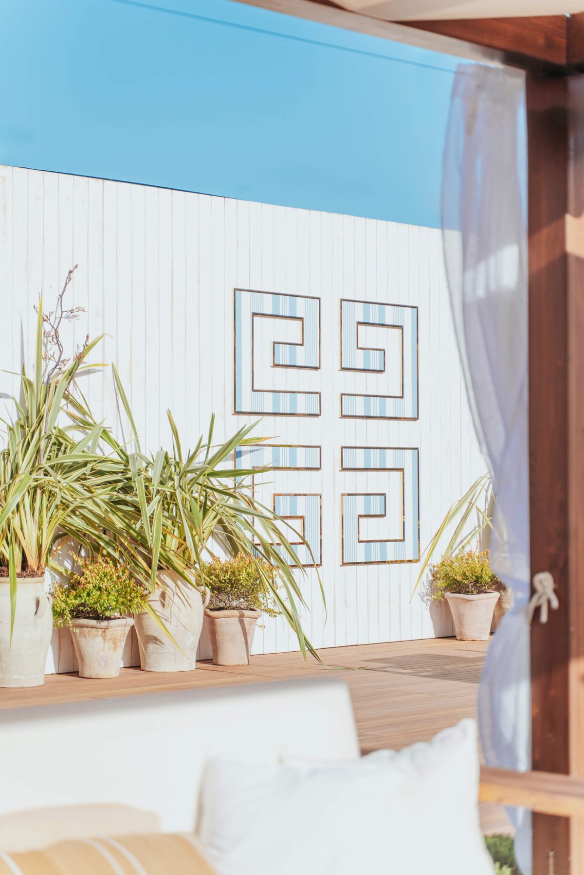 White wall with a light blue mosaic pattern and plants