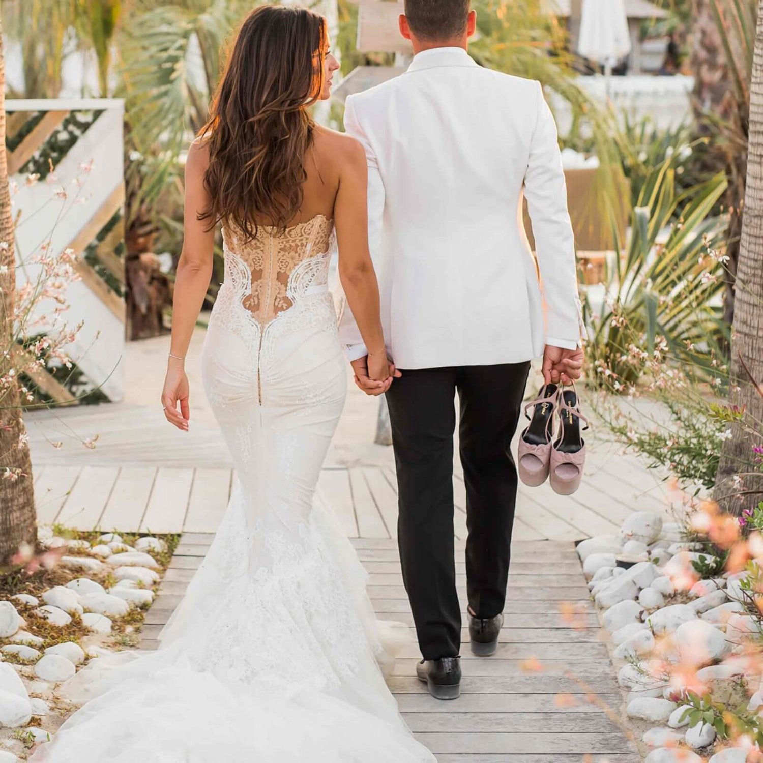 Back shot of a bride and groom holding hands walking away from the camera