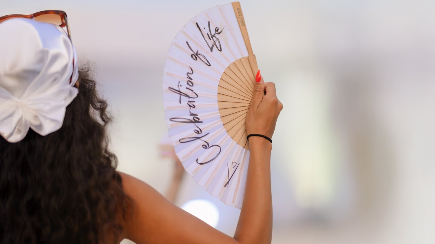 Woman from behind holding a fan in her hand