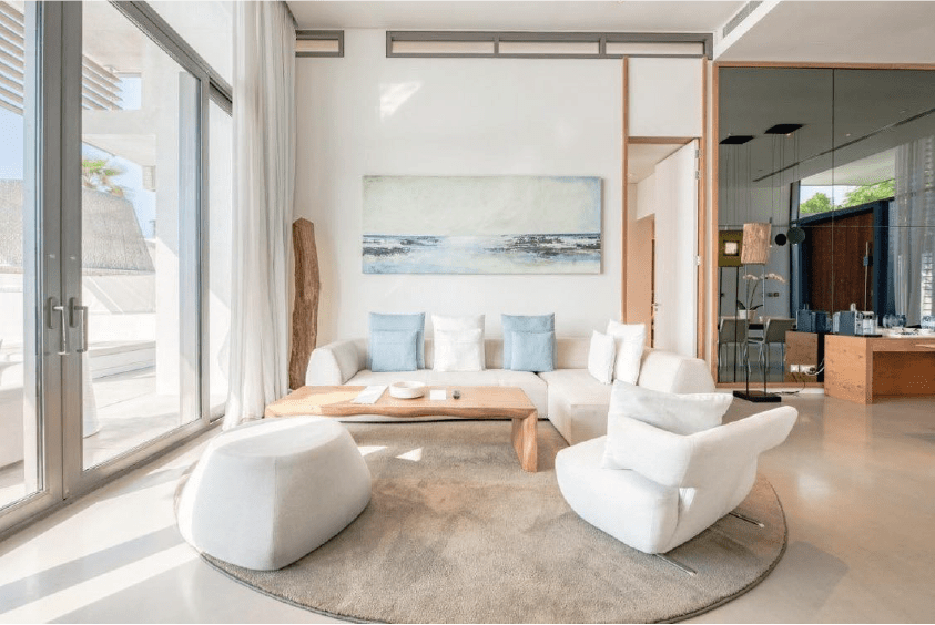 Sofa, arm chair and coffee table next to floor to ceiling glass doors